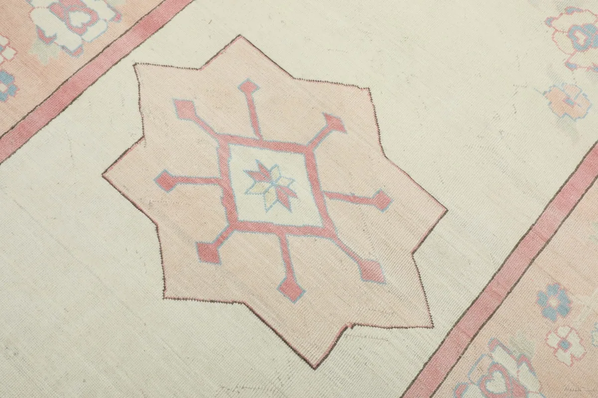 Close-up of the central geometric star motif in rose and ivory on the rug's field