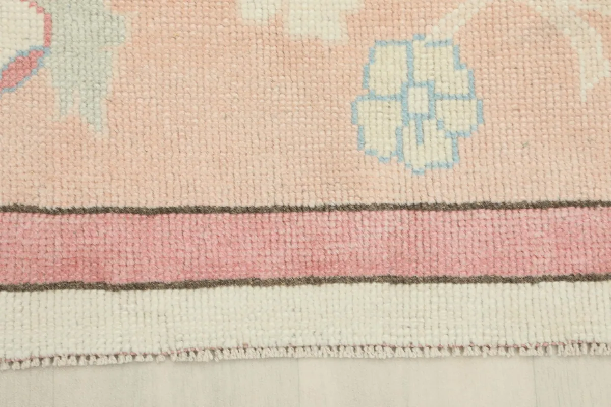 Close-up of the rug's rose border with a small blue floral detail and the edge finish