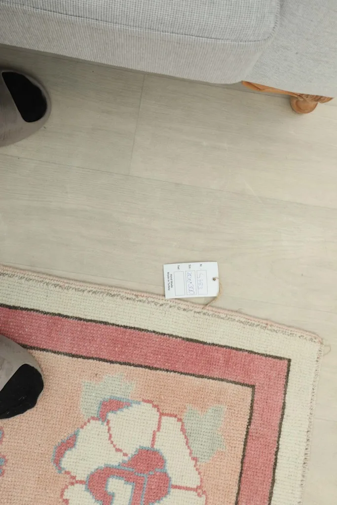 Overhead view showing a small tag near the rug's edge, next to a slippered foot