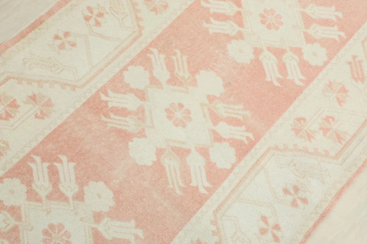 Diagonal view across the runner, emphasizing the repeated geometric motifs in rose and ivory