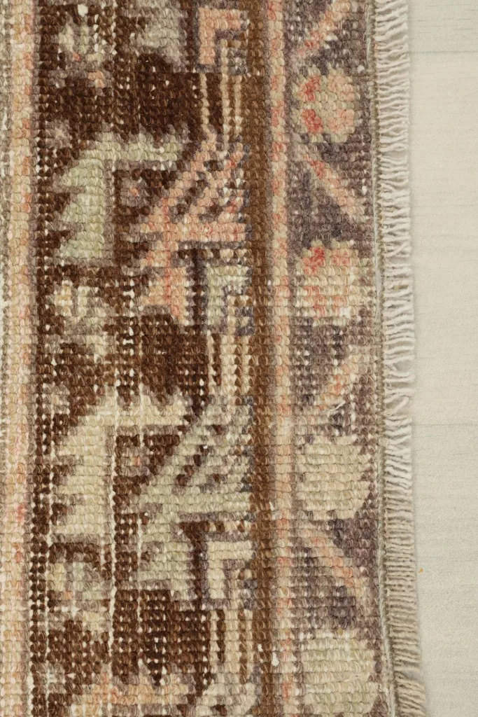Close-up of the rug's short, natural fringe and the intricate patterns of the border