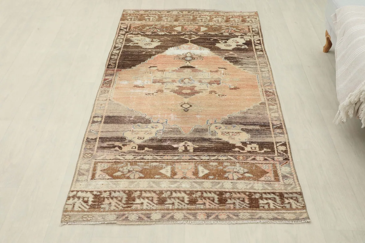 Full overhead view of the rust and brown vintage rug, laid flat on a light background