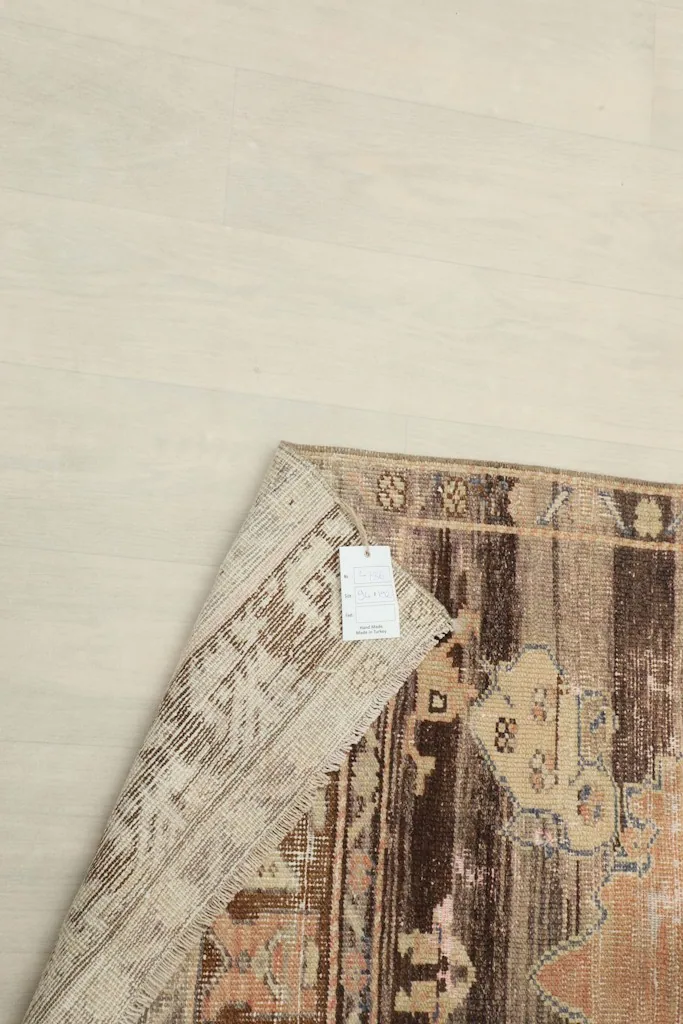 Corner of the rug folded back with a tag attached, showing the back of the rug