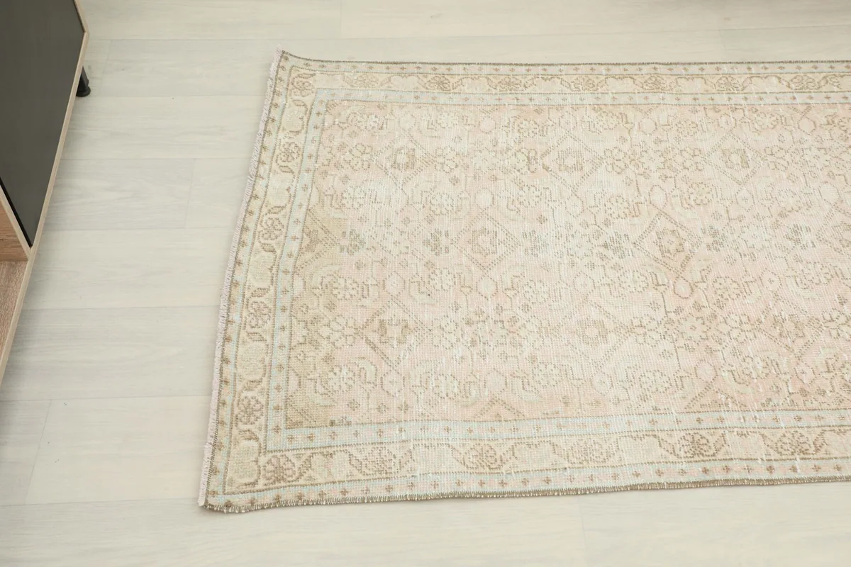 Close-up angled view of the beige section of the runner rug, highlighting geometric motifs and border.