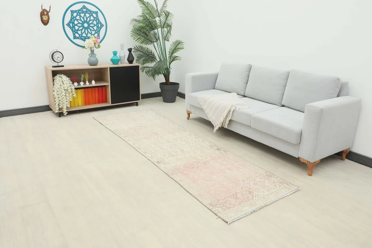 Rose and beige vintage runner rug in a modern living room setting next to a sofa.