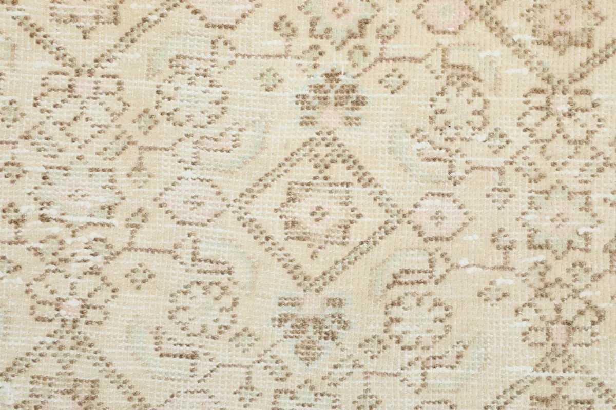 Macro detail shot of the hand-knotted wool pile and the intricate beige geometric design.