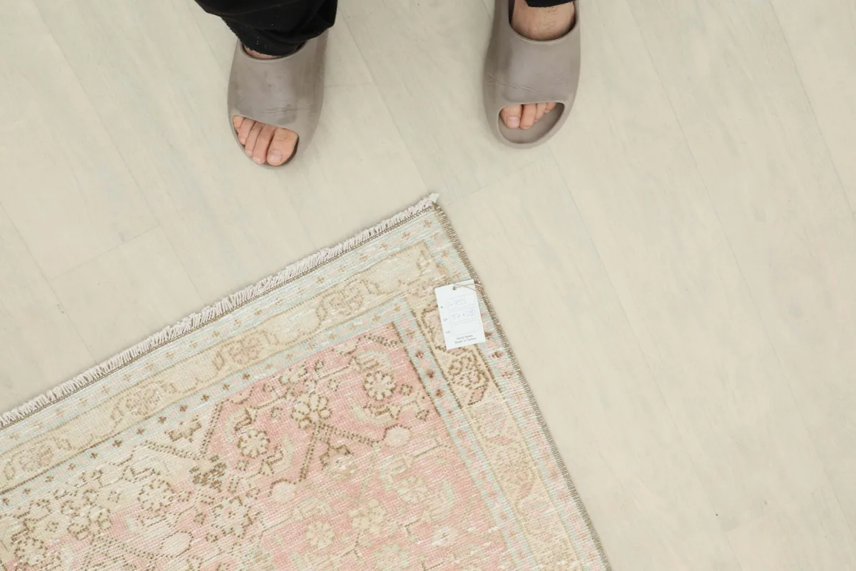 Overhead view of a person's feet next to the runner rug, showing scale and texture.