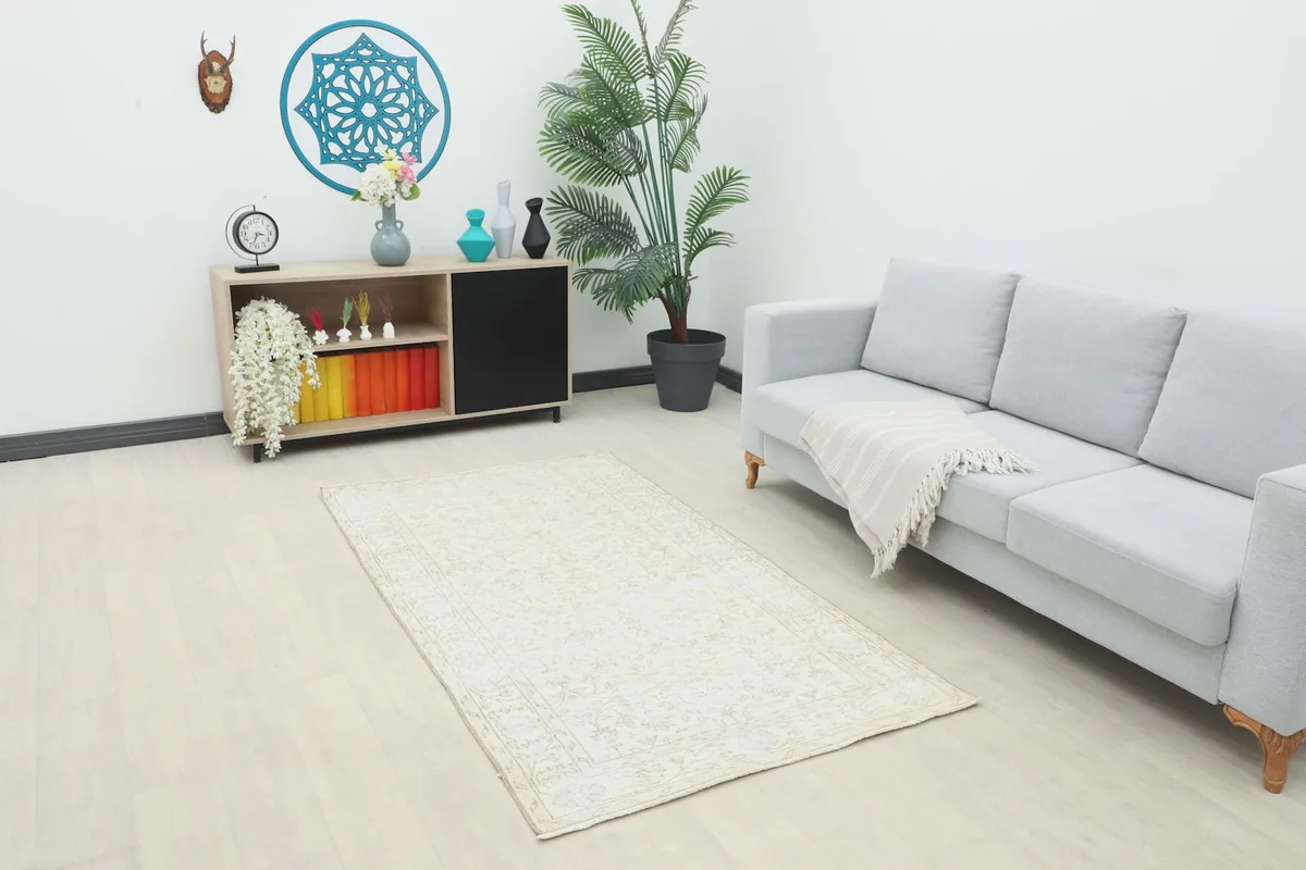 Ivory vintage rug placed in a modern living room setting with a gray sofa