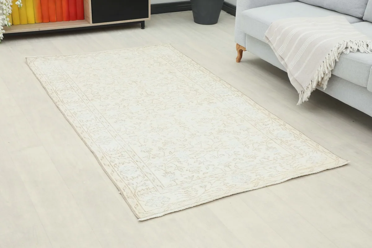Angled view of the ivory rug in a room, highlighting its placement next to a sofa