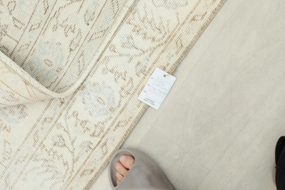 Overhead shot of the rug with a size tag and a foot for scale