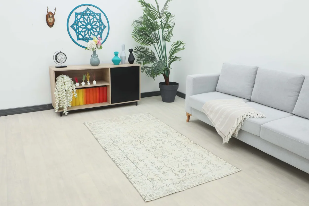 Ivory floral vintage rug displayed in a modern living room setting with a gray couch and wooden cabinet