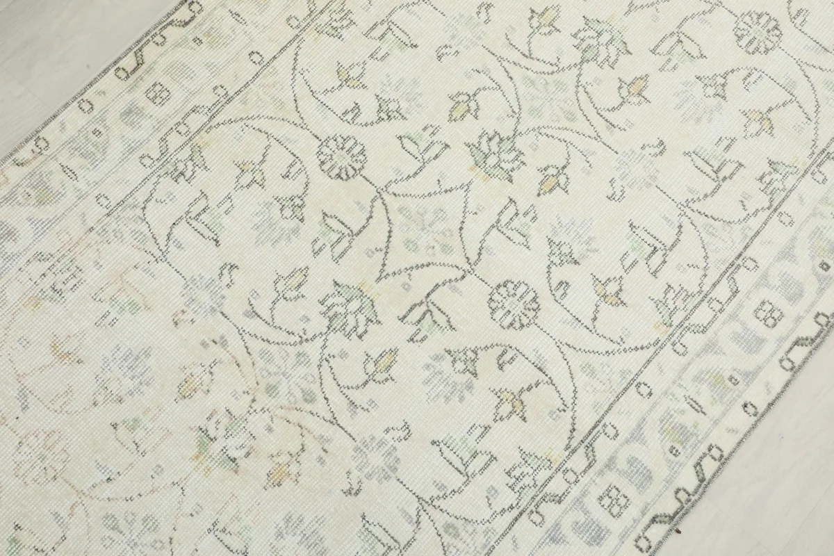 Close-up of the central floral and vine motifs within the ivory field of the vintage rug