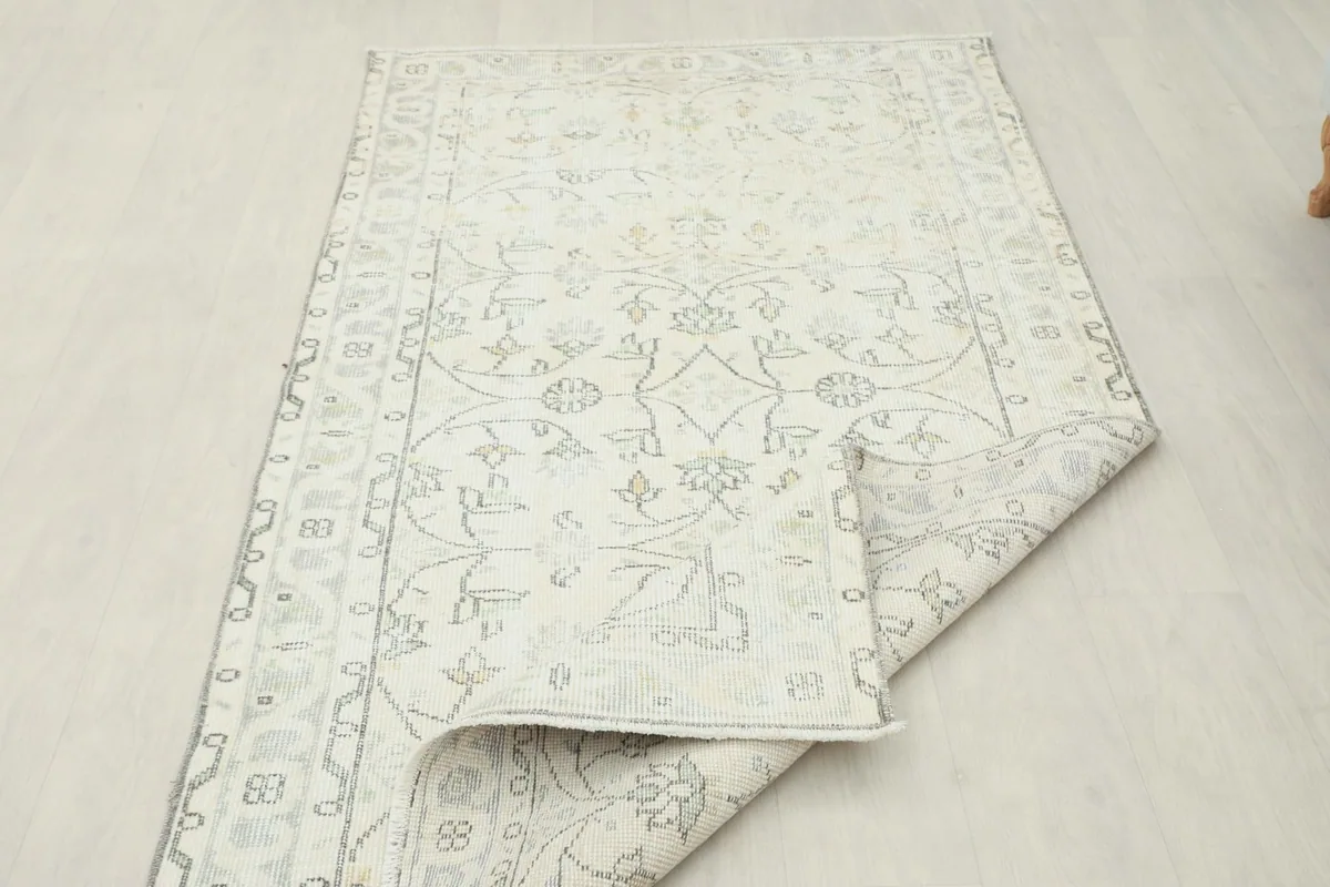 Partial fold of the rug revealing the reverse side, showing the hand-knotted construction