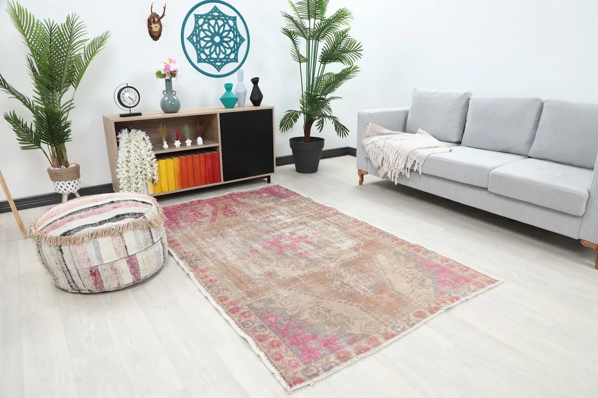 Angle view of the tan and rose vintage rug in a living room with a sofa