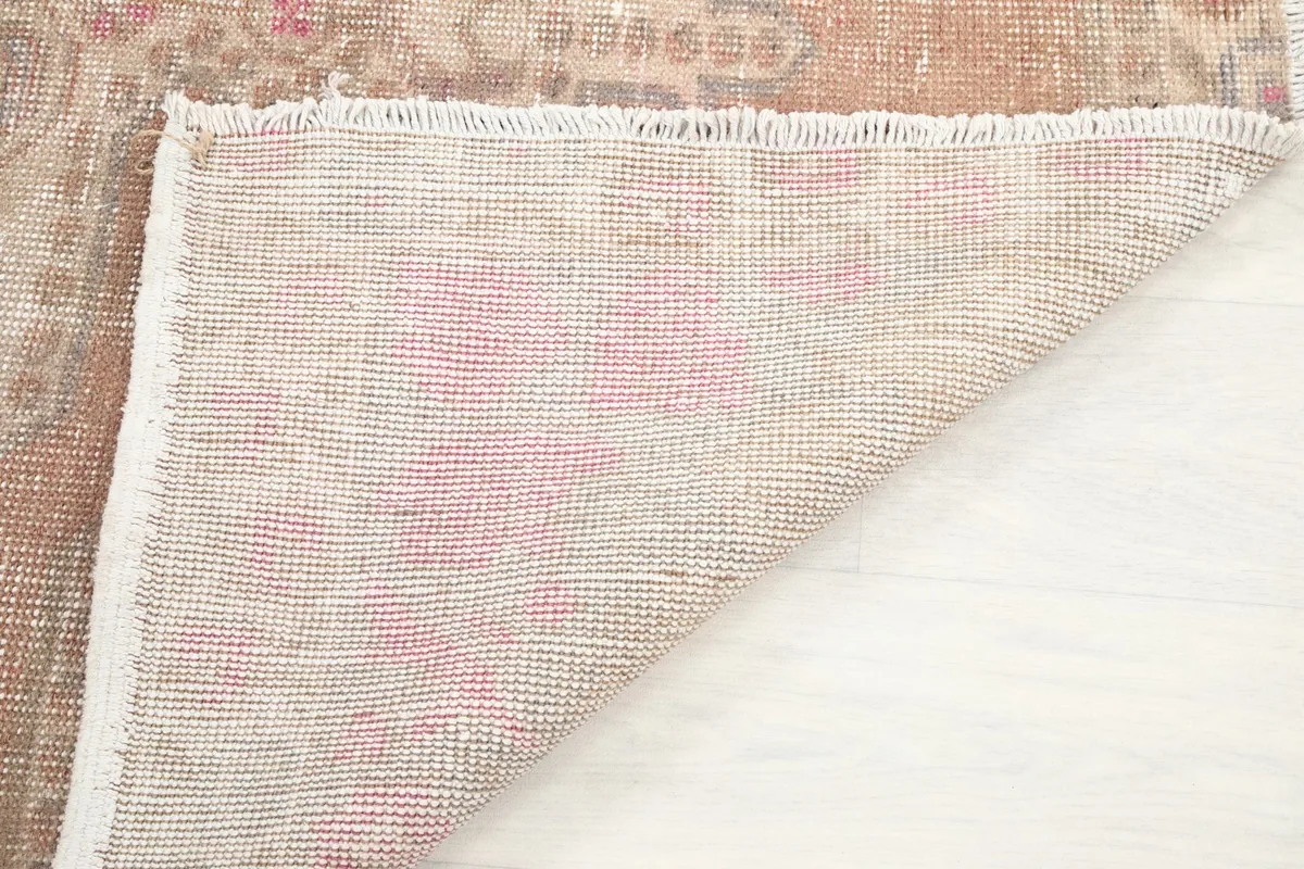 Corner of the rug folded back to reveal the hand-knotted cotton foundation