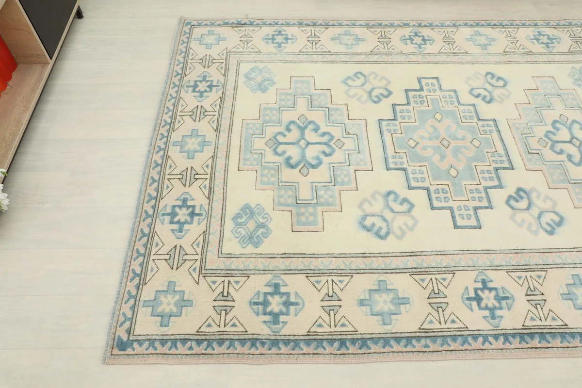 Another angle view showing the intricate blue and ivory tribal border details of the hand-knotted rug.