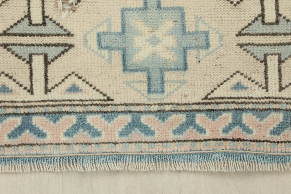 Close-up of the short, natural wool fringe and the edge of the blue and rose patterned border.