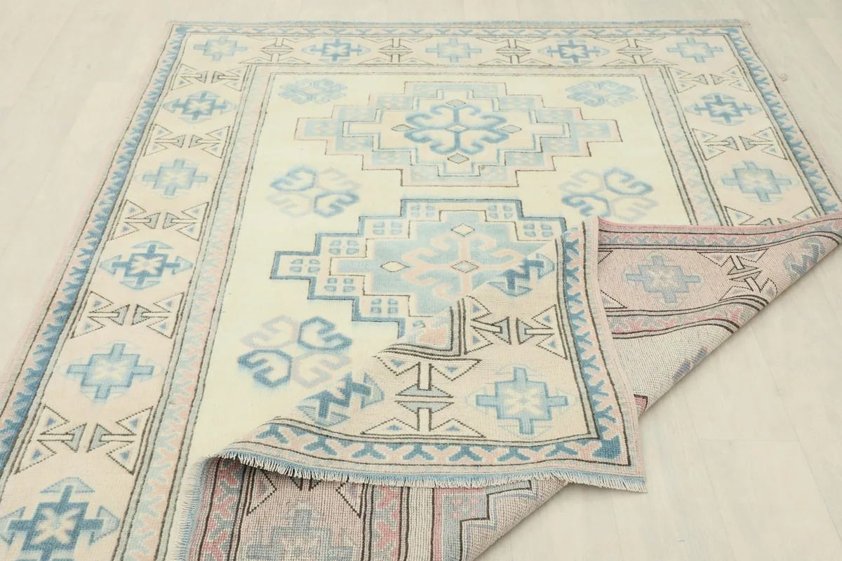 The rug partially folded to show the thickness and texture of the vintage wool pile.
