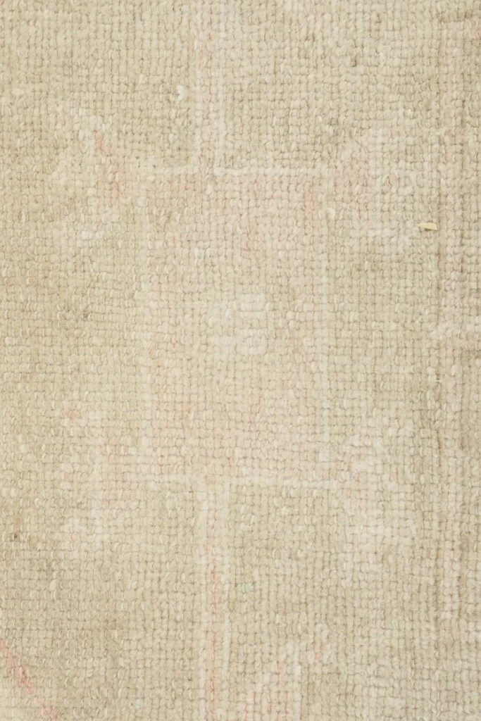 Close-up texture of the low wool pile and the subtle, worn surface of the vintage rug.