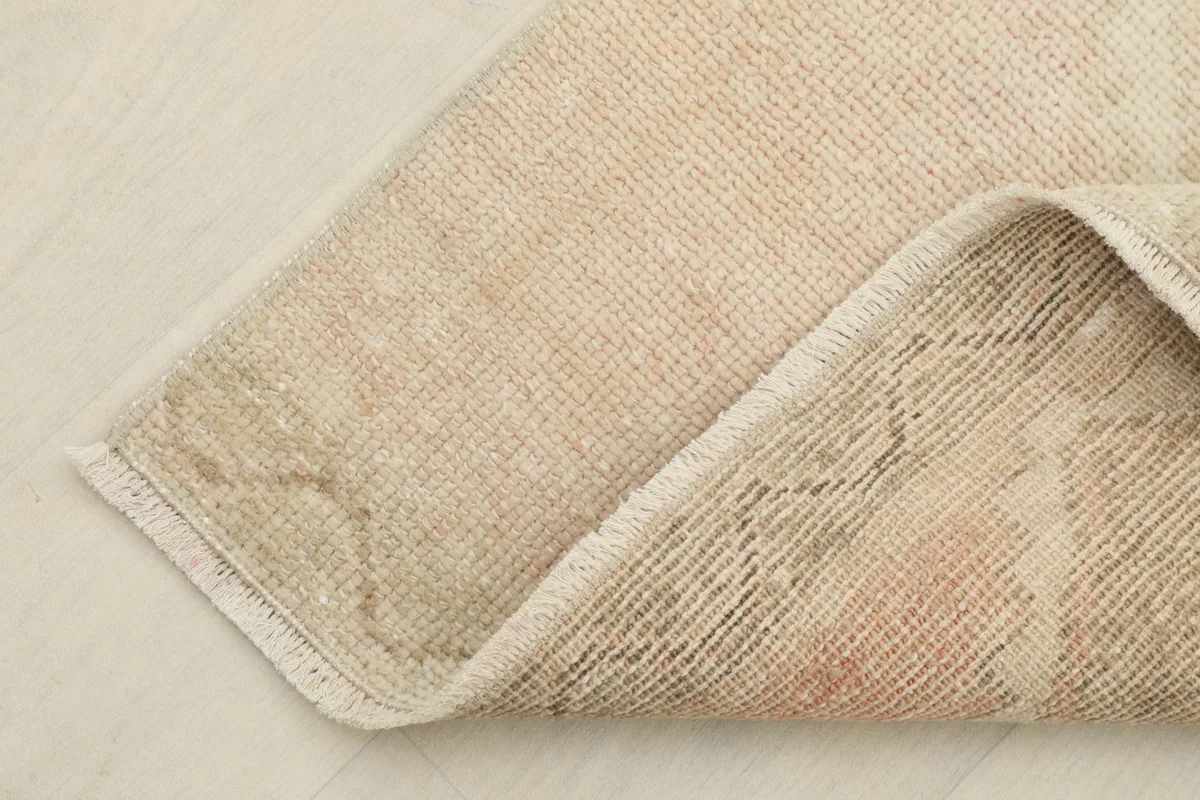 Corner of the rug folded to reveal the cotton foundation and the reverse side of the knotting.