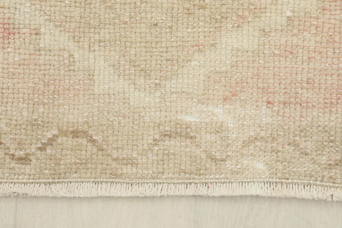 Close-up view of the short, natural fringe and the edge of the hand-knotted rug.