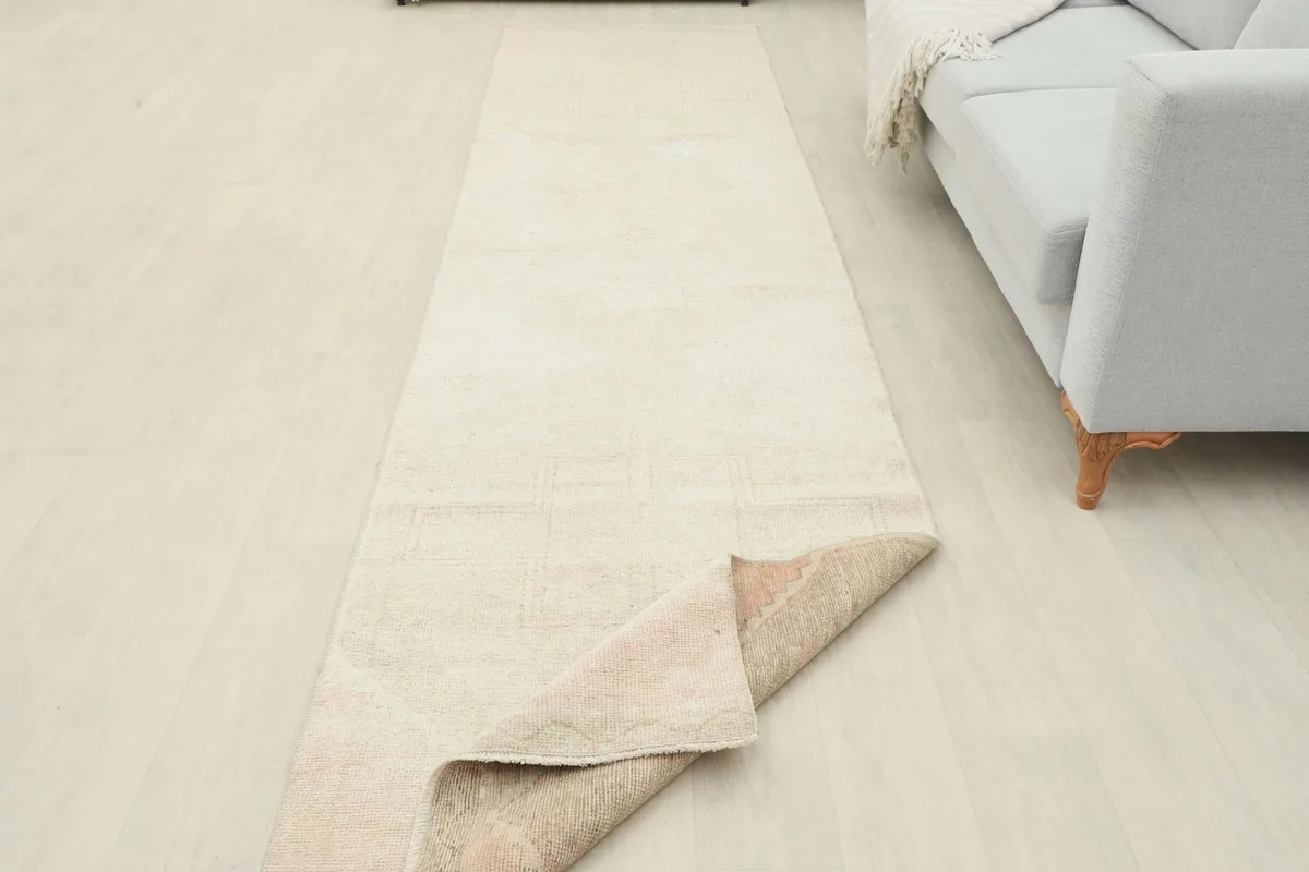 Runner rug partially folded back in a room setting, showing the underside and thickness.