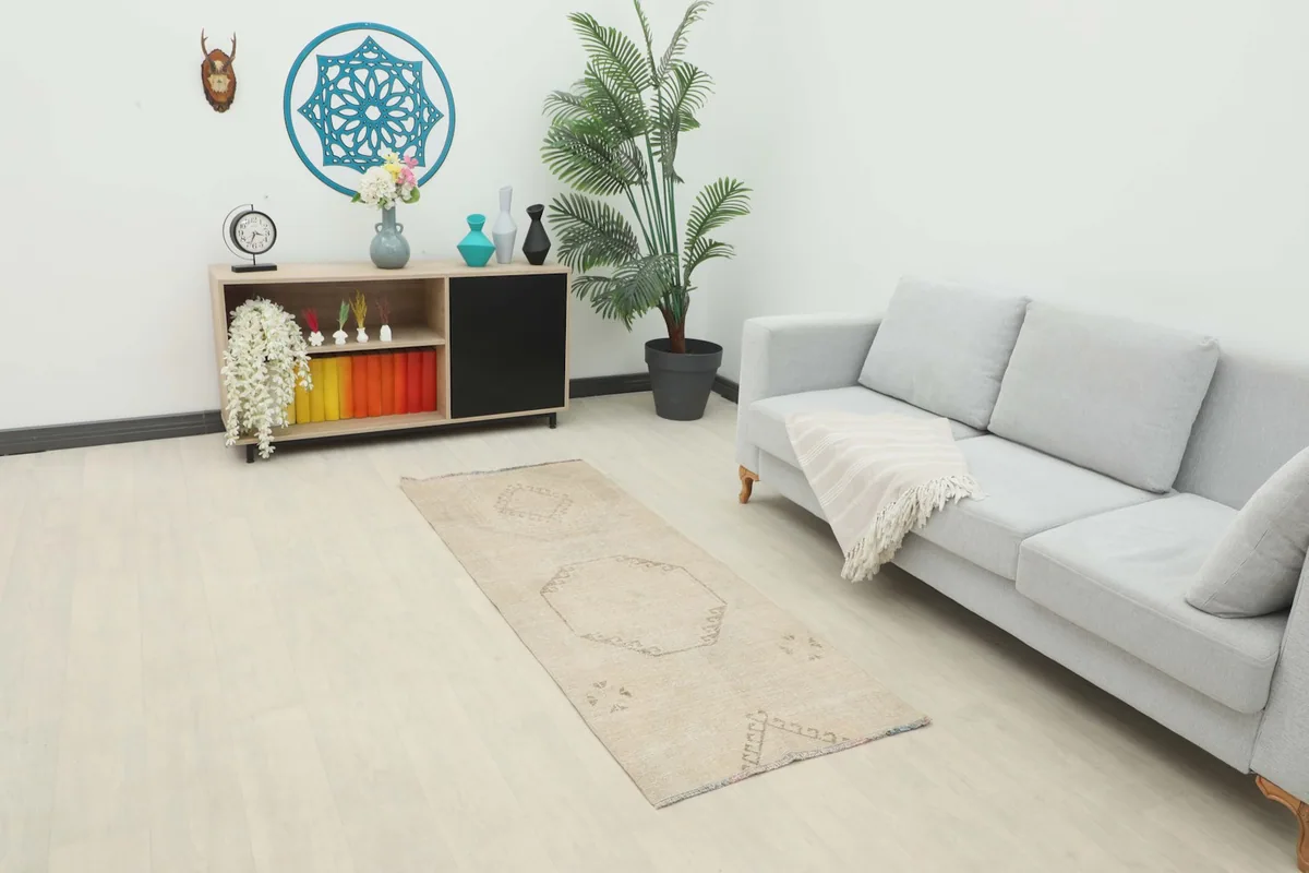 Runner rug placed in a modern living space next to a sofa and cabinet, showing its scale.