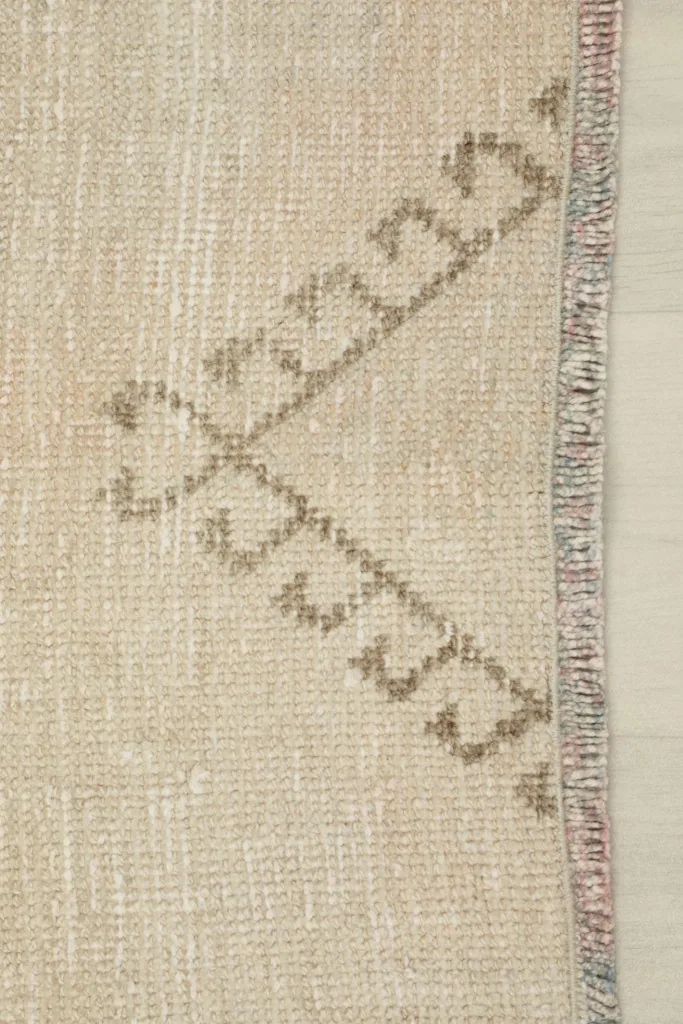 Close-up of the rug's short edge, revealing the subtle weave and faint colors in the binding.
