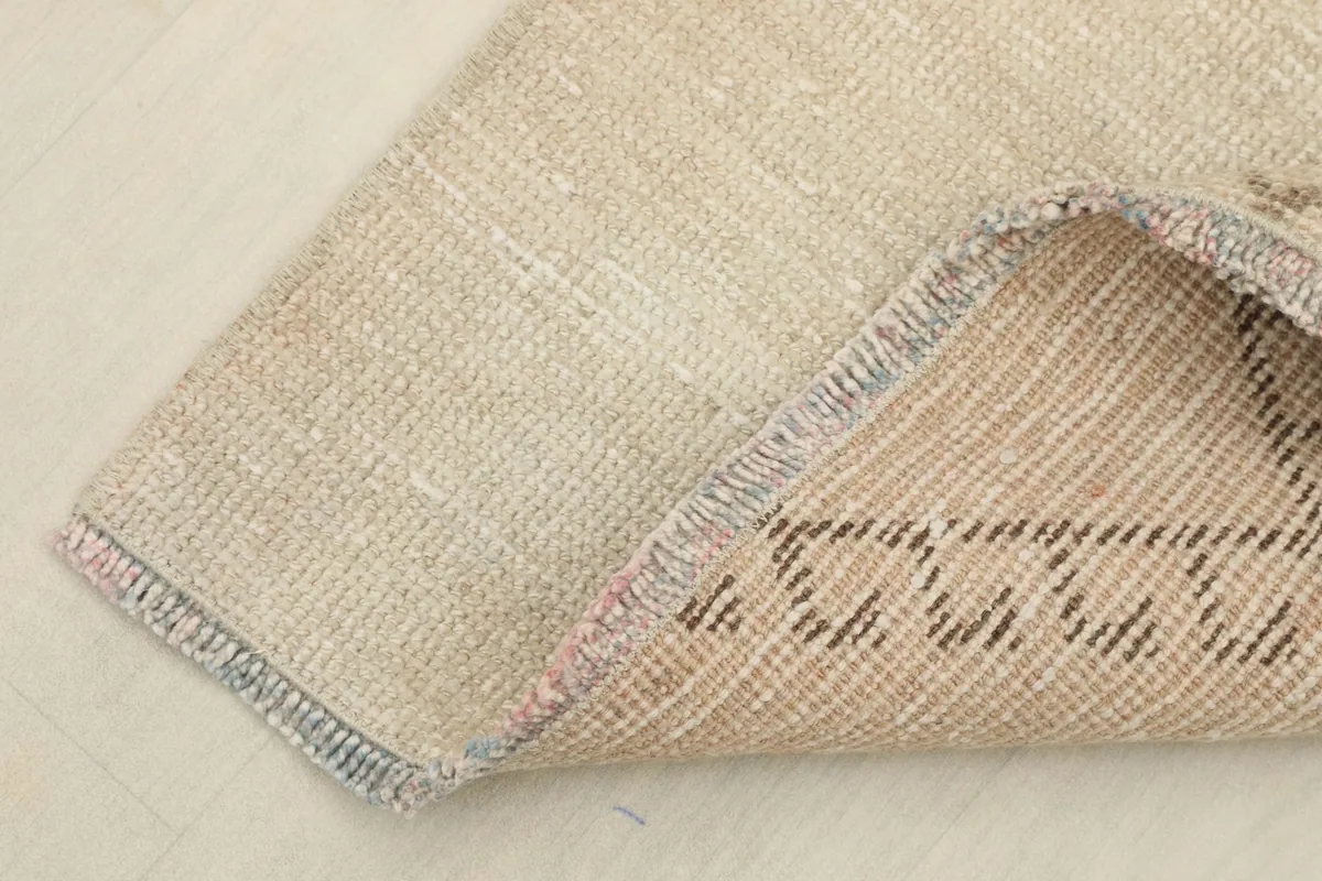 Corner of the rug folded back to show the hand-knotted cotton foundation and wool pile.
