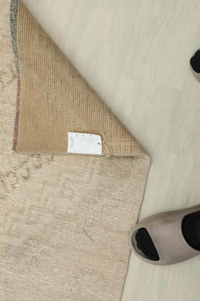 Overhead view of the rug's underside, revealing the tightly woven cotton foundation and a product tag.