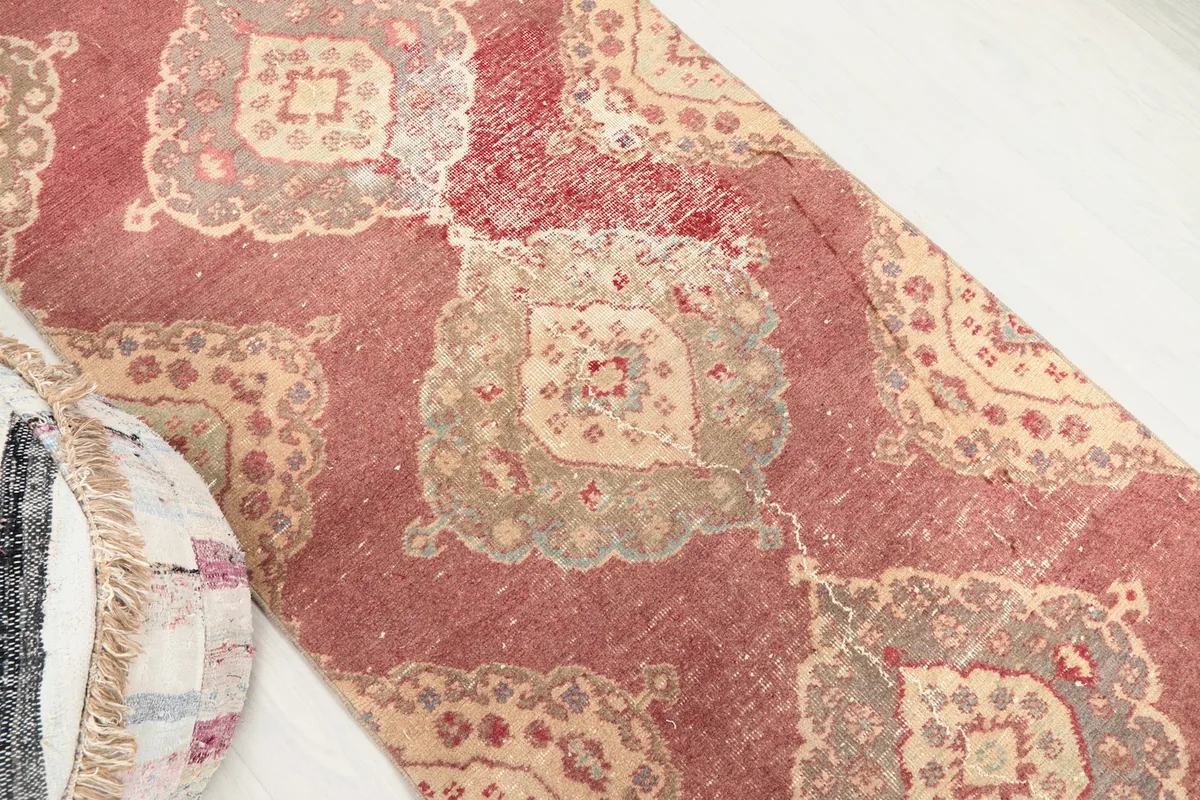 Close-up view of a rose and beige medallion pattern with visible wear and patina