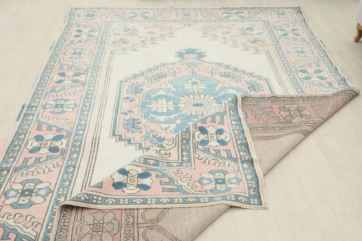 View of the rug's back and foundation, with a corner lifted to show the hand-knotted construction.