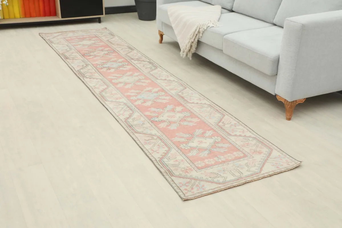 Angled view of the rose runner in a room, showing its length next to a sofa