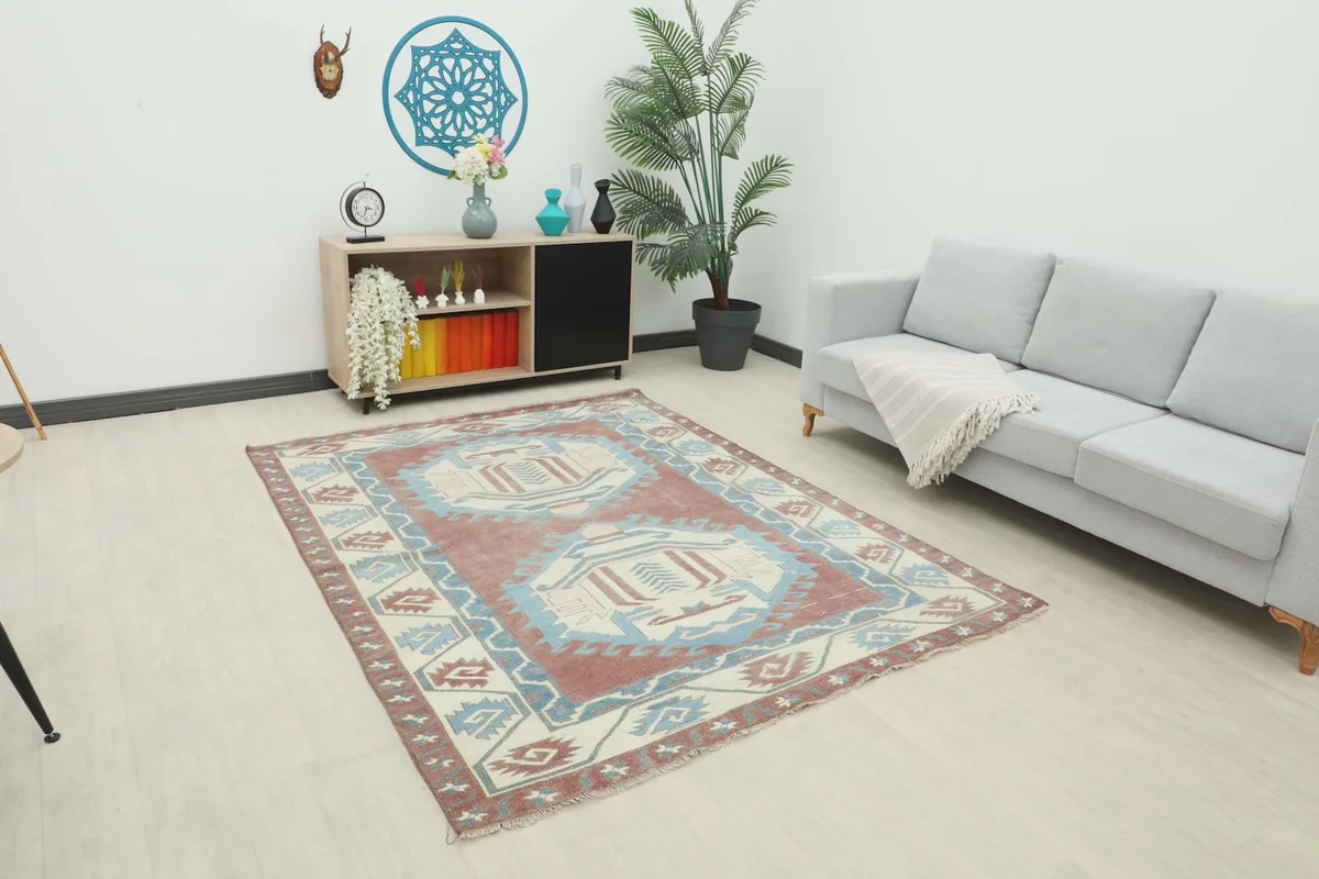 Vintage Anatolian rug displayed in a bright living room setting with a sofa and cabinet.