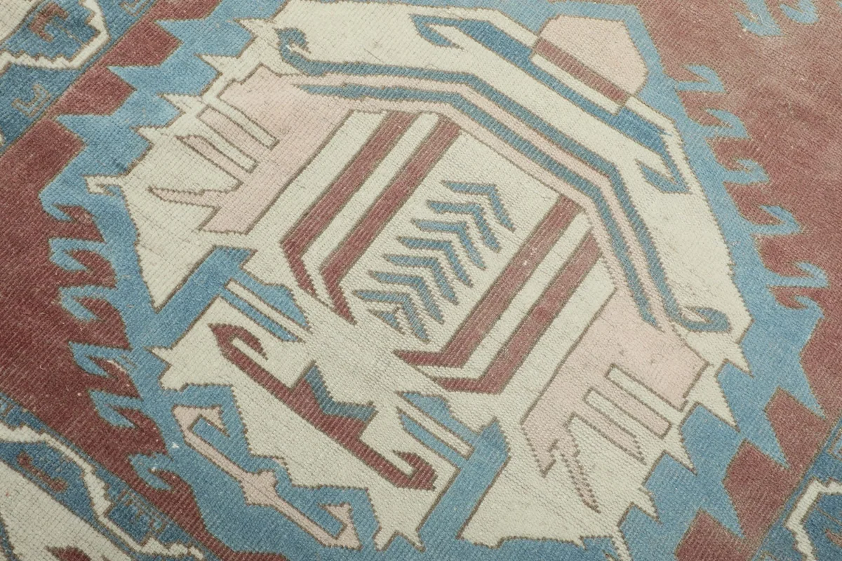 Close-up of a central geometric medallion with blue and ivory patterns on the rust field.