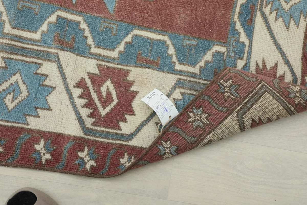 Close-up of the rug's reverse side, revealing the hand-knotted construction and a product tag.