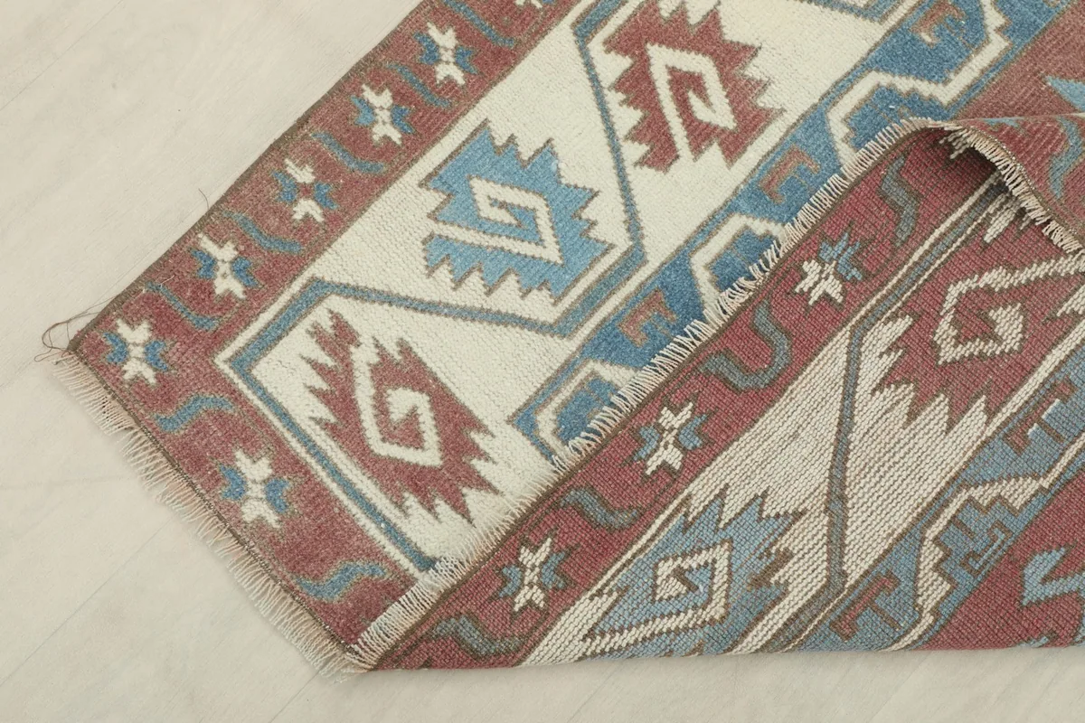 Corner of the rug folded back, showing the back of the hand-knotted cotton foundation and wool pile.