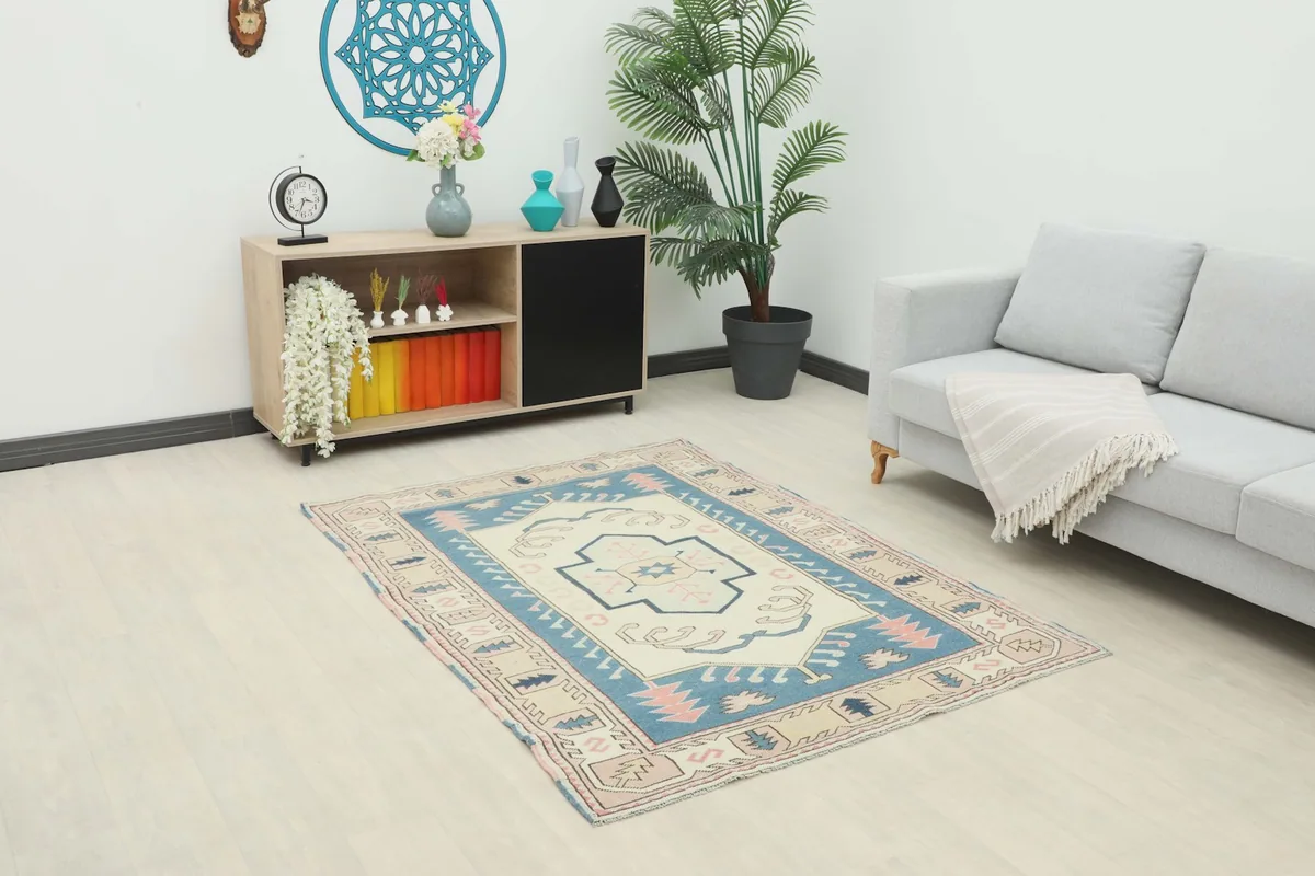 Vintage Anatolian rug displayed in a bright living space with a sofa and cabinet.