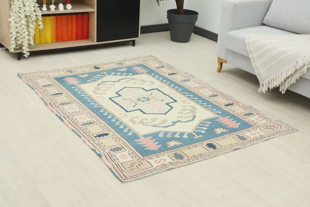 Angle view of the ivory, blue, and rose rug in a room setting, showing its placement.