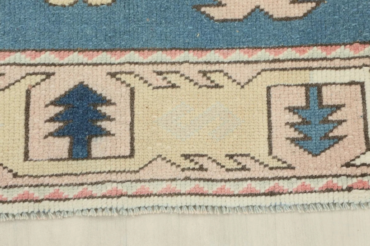 Close view of the outer border with small tree-like motifs and a subtle rose guard band.