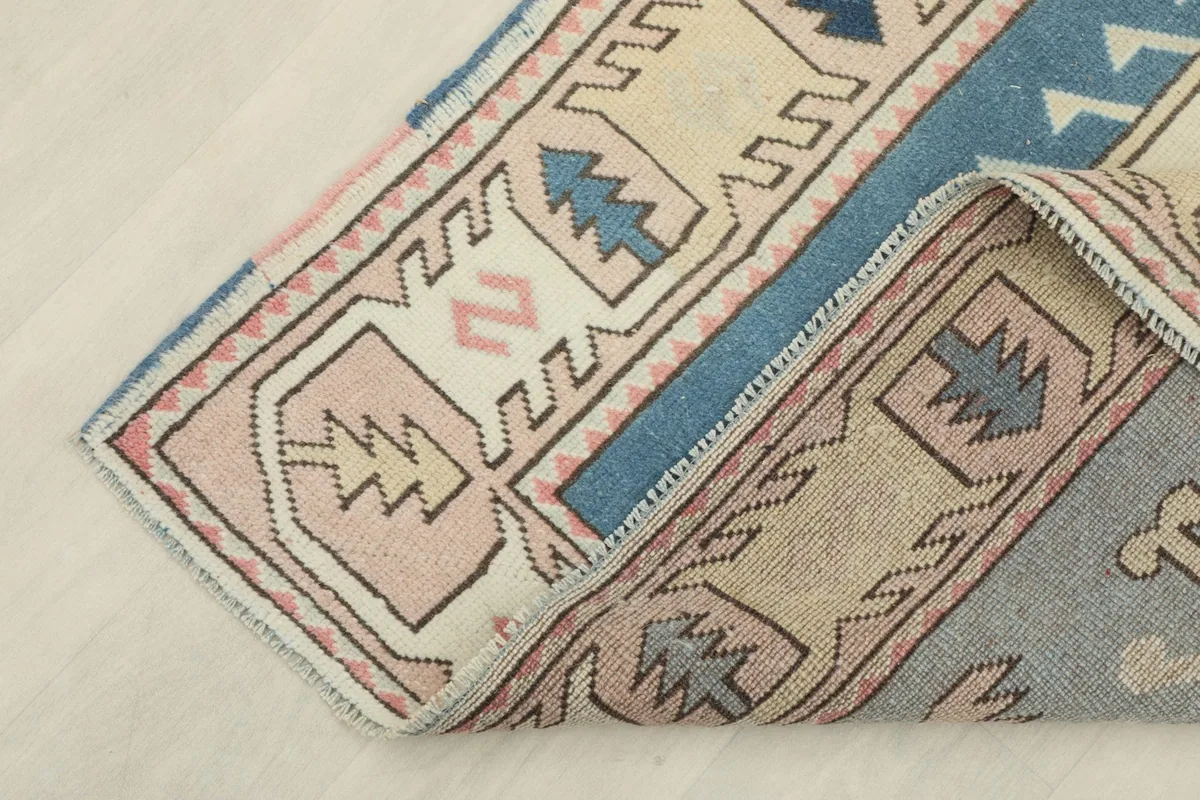 Corner of the rug folded back, revealing the reverse side and cotton foundation.