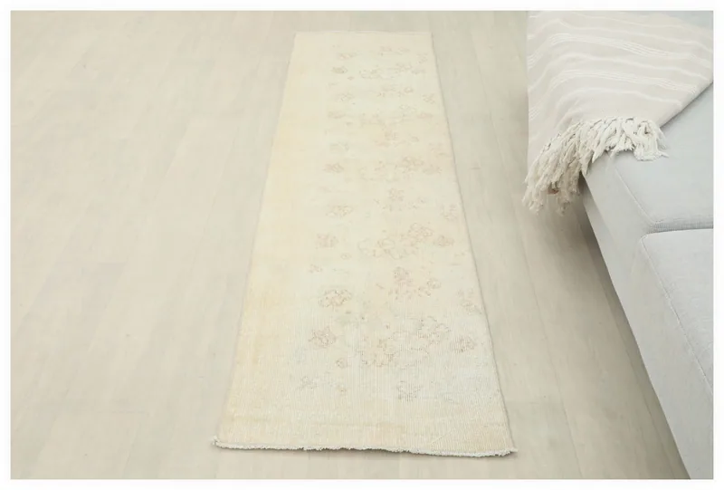 Full overhead view of the 1'10" x 6'7" vintage ivory runner rug on a white background.