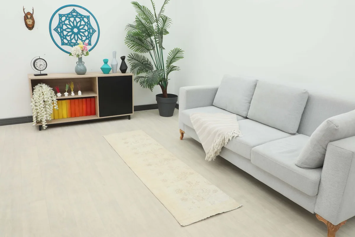 Ivory runner rug placed in a living room scene, extending from a light gray sofa.