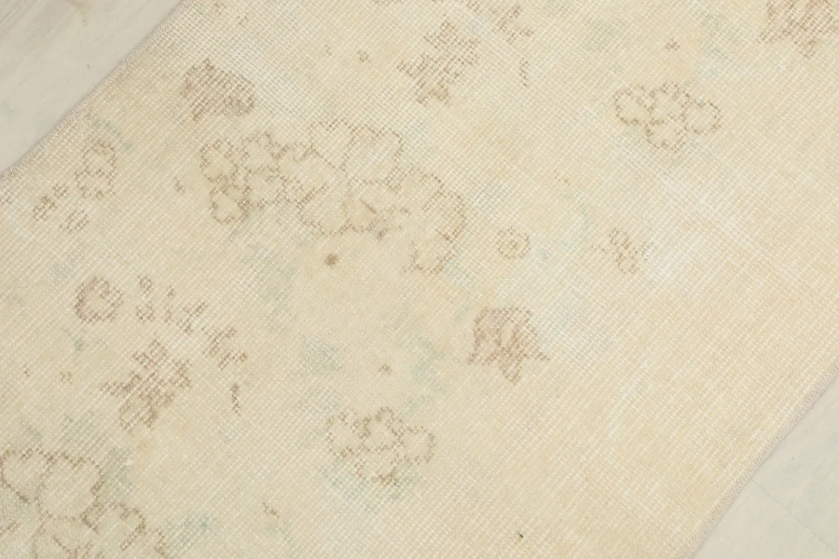 Macro shot of the rug's surface, revealing the intricate, faded floral and geometric patterns.