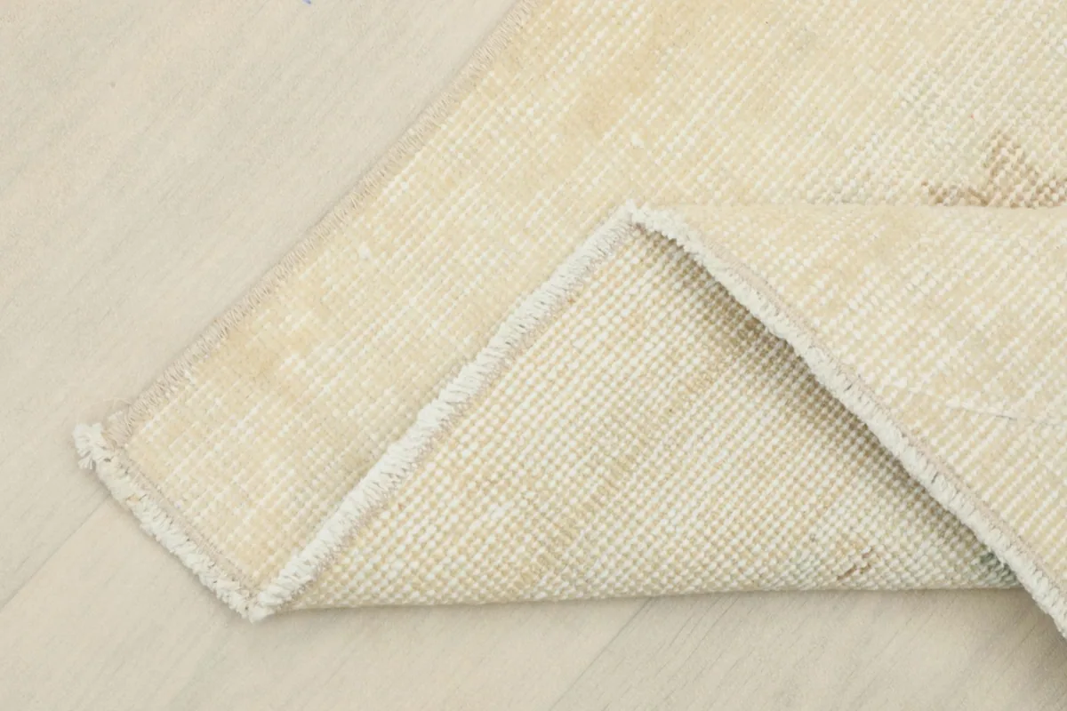 Corner of the rug folded to show the hand-knotted wool pile on its cotton foundation from the reverse side.