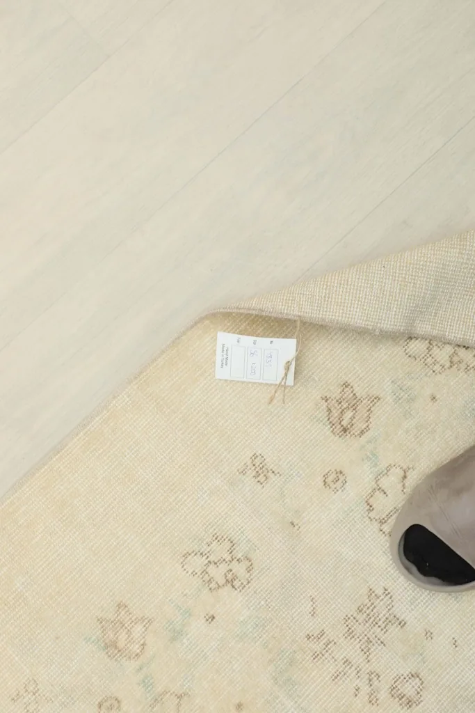 Close-up of the rug's surface with a foot, showing the scale and the subtle design elements.