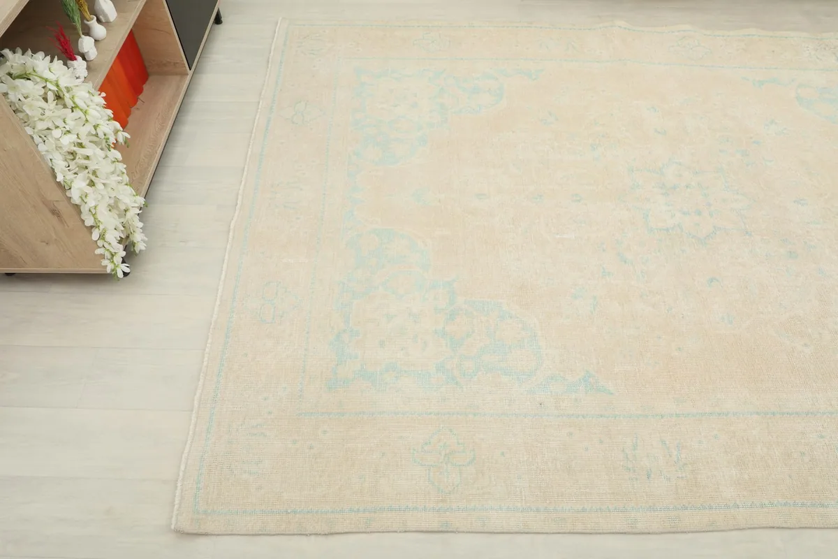 Side angle view of the rug, highlighting the soft beige field and faded blue patterns.