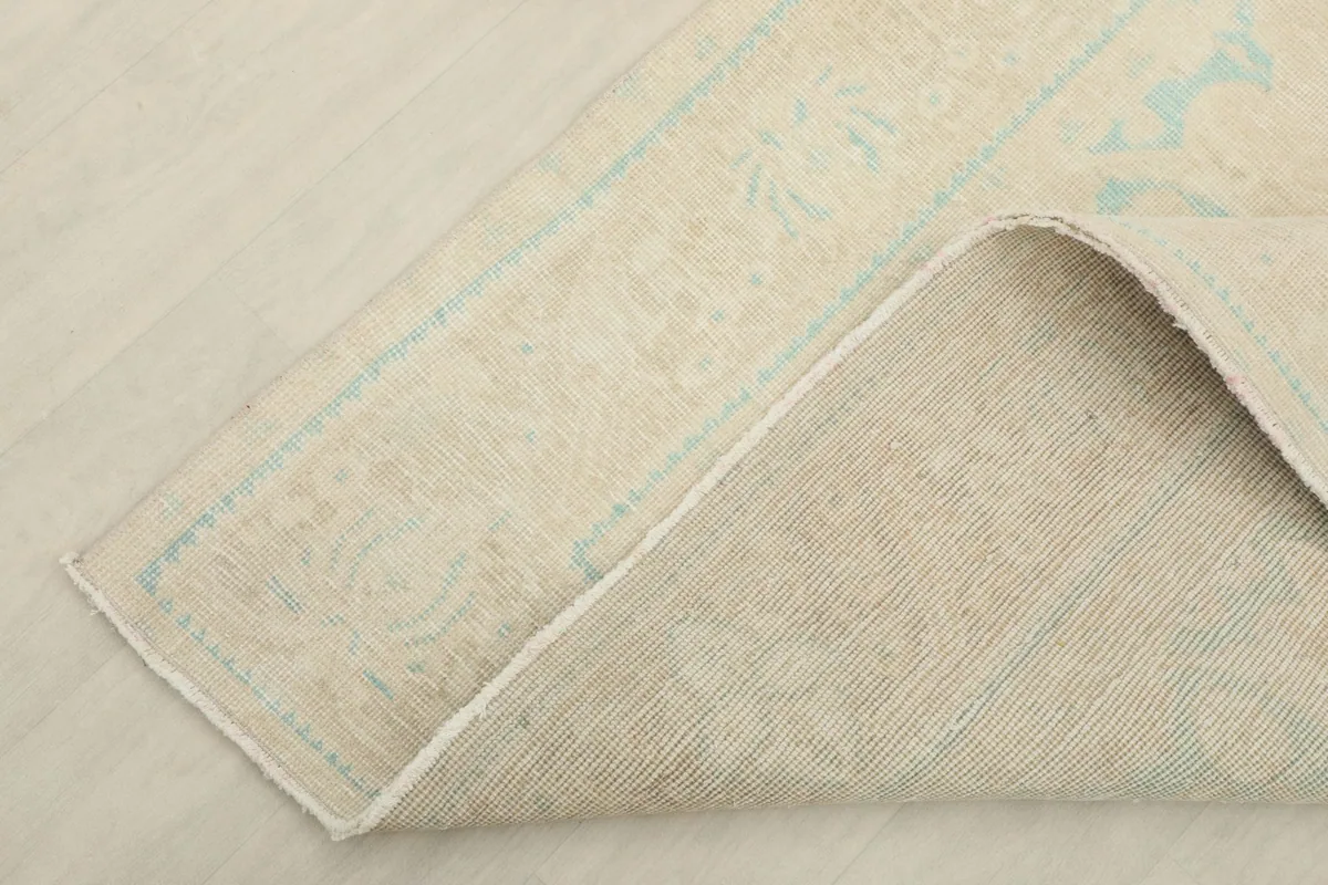 Corner of the rug folded to reveal the cotton foundation and reverse side of the knots.