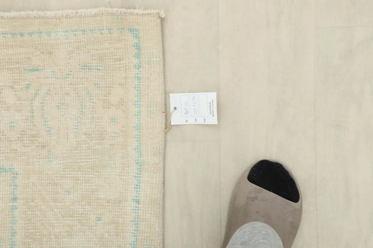 Overhead view showing the rug's label and a foot for scale, emphasizing its size and craftsmanship.