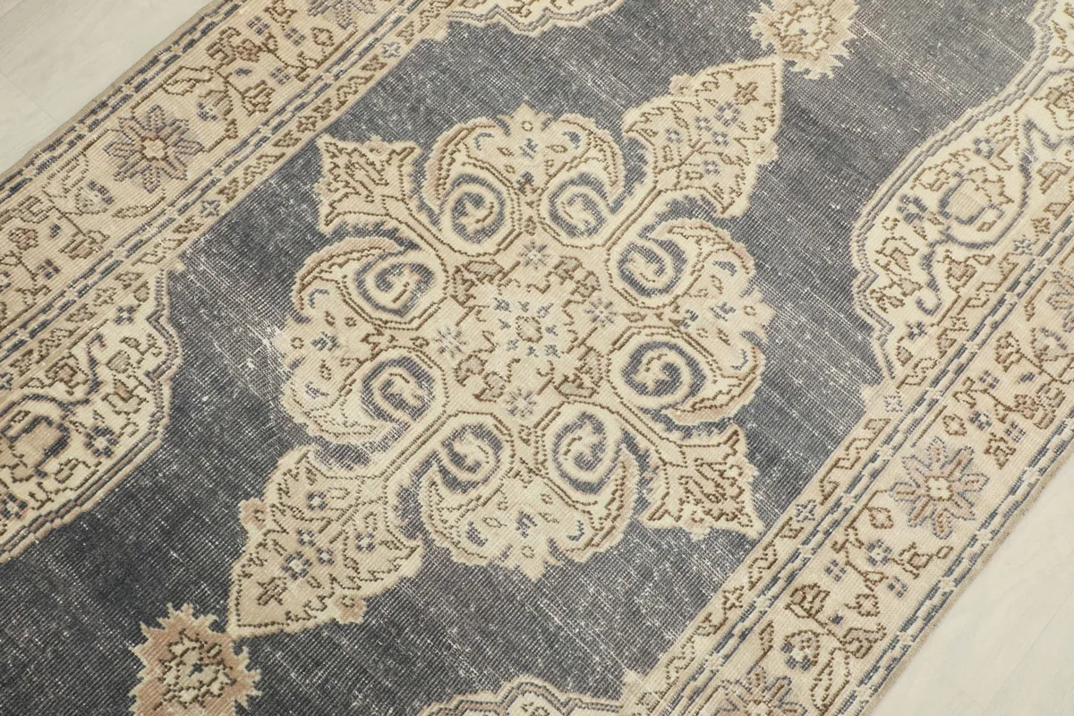 Detailed close-up of the central medallion design in ivory and beige on the charcoal field.